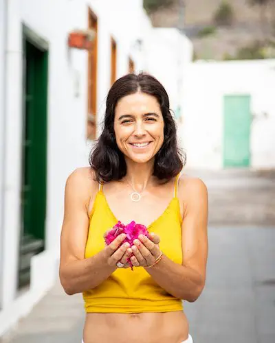 Mujer sosteniendo pétalos entre las manos — símbolo de lo que florece en la espera y de la confianza en los procesos lentos.