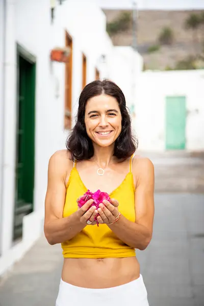 Mujer sosteniendo pétalos entre las manos — símbolo de lo que florece en la espera y de la confianza en los procesos lentos.